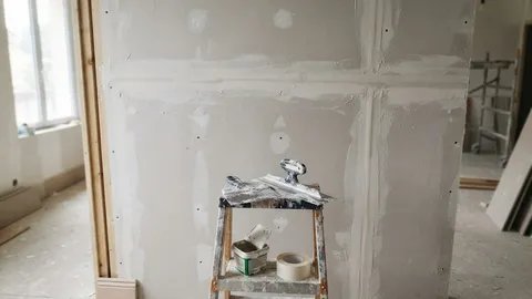 Cloison en plaques de plâtre en cours de finition, couteau à enduire