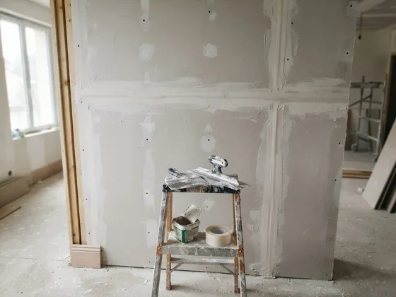 Cloison en plaques de plâtre en cours de finition, couteau à enduire